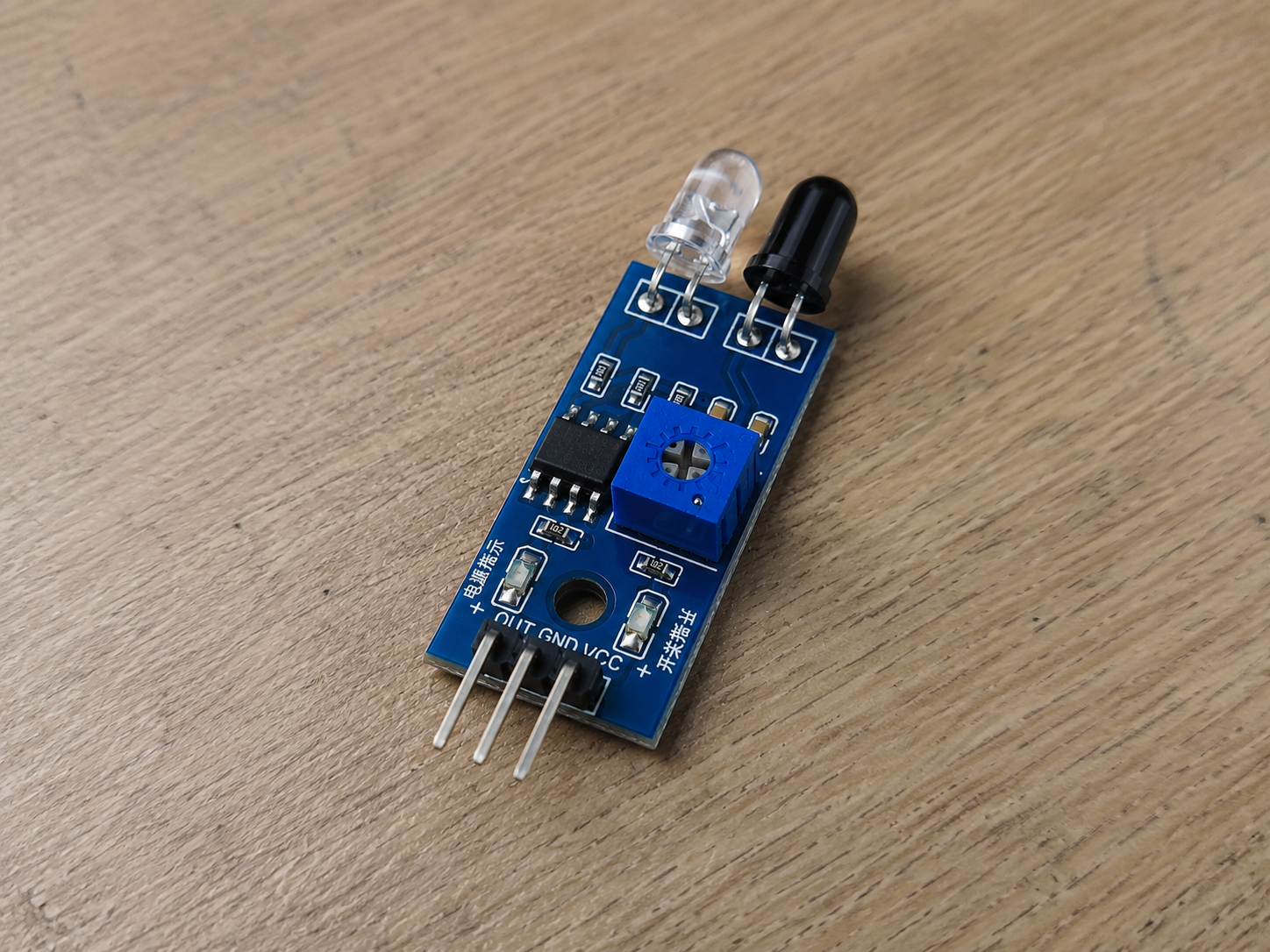 IR sensor module on a wooden desk showing the 3 pin header, trimpot, IR LED, and receiver used for obstacle detection